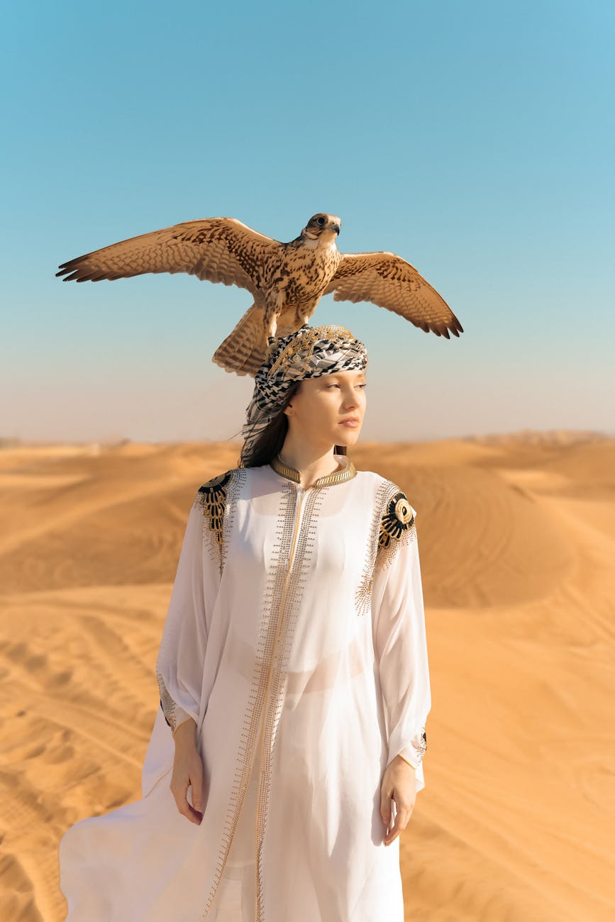 elegant woman with falcon in dubai desert landscape